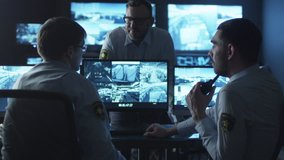 Group of security officers are having a conversation at work in a dark monitoring room filled with display screens. Shot on RED Cinema Camera in 4K (UHD).