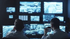 Two security officers noticed a trespasser on a surveillance computer screen in a dark monitoring room. Shot on RED Cinema Camera in 4K (UHD).