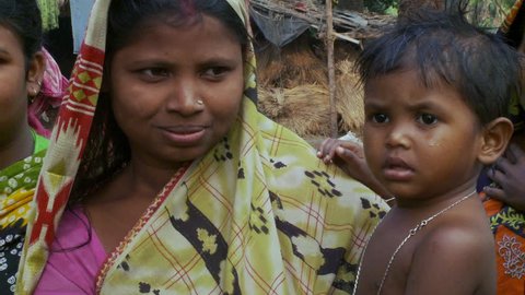 Baruipur, India - CIRCA 2013 - Mother in the jungle with child in arms smiles and looks at camera