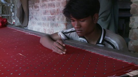 Baruipur, India - CIRCA 2013 - Close up view of mans hand sewing sequins on fabric