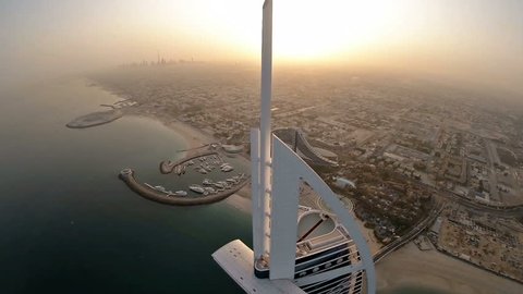 Fly over Burj Al Arab hotel in Dubai, UAE. Burj Al Arab is a luxury 5 star hotel built on an artificial island in front of Jumeirah beach. Helicopter aerial view at sunrise