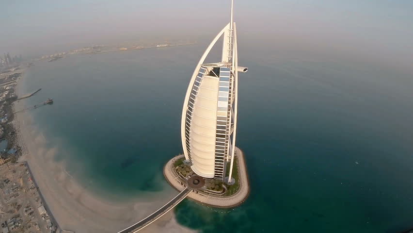 Fly over Burj Al Arab hotel in Dubai, UAE. Burj Al Arab is a luxury 5 star hotel built on an artificial island in front of Jumeirah beach. Helicopter aerial view at sunrise