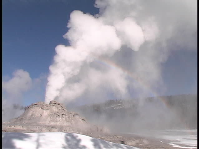 A rainbow forms behind the Castle Geyser in Yellowstone National Park.
