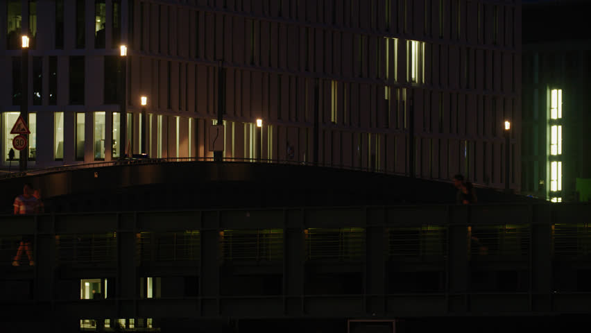 Berlin Street Scene At Night. Pedestrians, Bicycle Driver, Traffic, Crossing Bridge. Urban Landscape With Street Lights. Summer