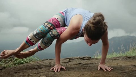 Fit yoga girl doing power pose on top of hill
