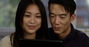 Happy young Asian couple having a video chat on a digital touchscreen. Shot on RED Epic.