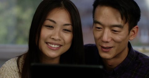 A happy young Asian couple video chatting with friends or family on their digital tablet. Shot on RED Epic. 스톡 비디오