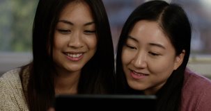 A happy young Asian couple video chatting with friends or family on their digital tablet. Shot on RED Epic.