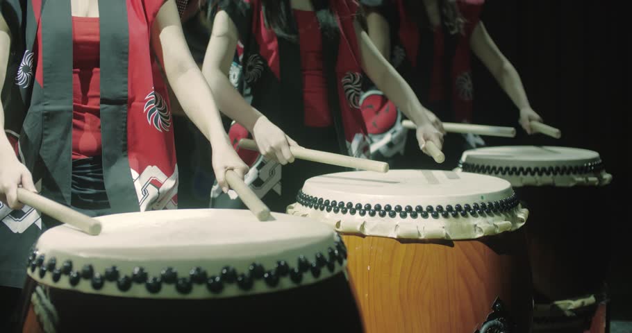 a group of Japanese Taiko drummers girls , start playing with the jump dark background, slow motion