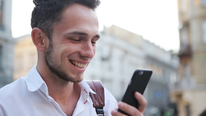 Young male person watching on a phone screen and laughing