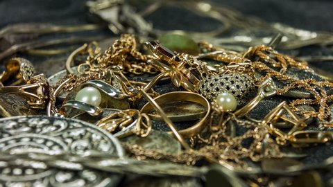 Old coins and gold treasures in a dark sand close-up rotation.