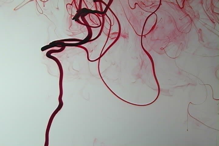 Red ink elegantly flowing in a liquified chamber.