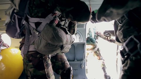 Paratroopers opening door in helicopter and jumping out with parachutes