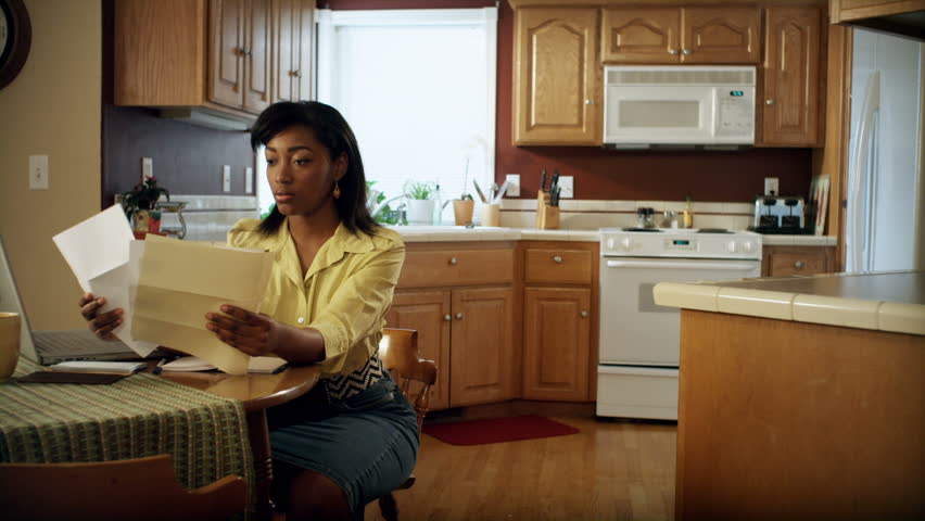 An African American woman performs various tasks around the house. She searches