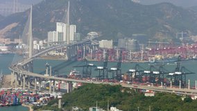 The famous Stonecutters Bridge of and commercial shipping container yards of Hong Kong in extreme zoom from high atop a distant skyscraper.