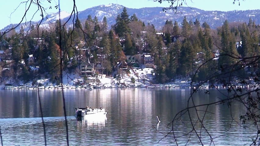 Man in pontoon boat going across lake in winter
