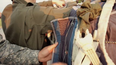 Closeup of military instructor checking paratroopers parachute