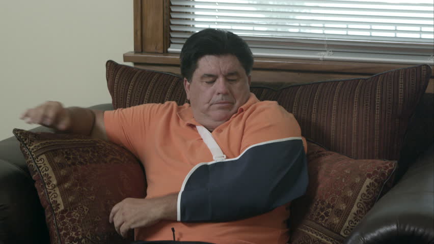 Man sitting in armchair with a sling on his arm.