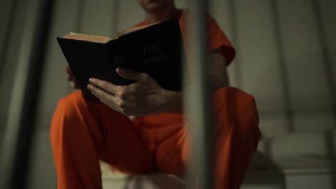 Scene of an inmate reading a bible in prison