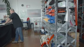 In this video, we can see a salesman in the store with agricultural machinery parts. Wide-angle shot.