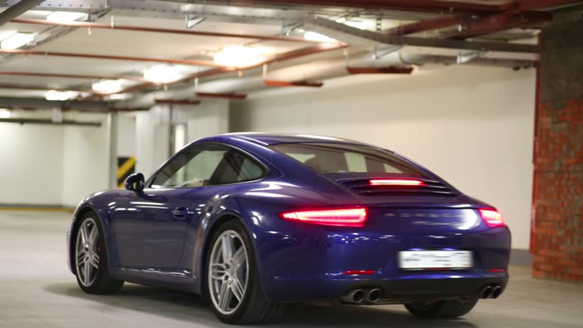 Blue sports car with burning rear lights in underground parking