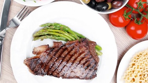 meat table : rare medium roast beef fillet and pasta with tomatoes asparagus and several kinds of olives served dish over light wood 1920x1080 intro motion slow hidef hd