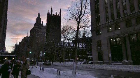 NEW YORK - JAN 25, 2016: First Presbyterian Church with snow on Lower 5th Ave women walking at sunset and talking in winter NYC. Gothic architecture can be seen around Manhattan in the city.