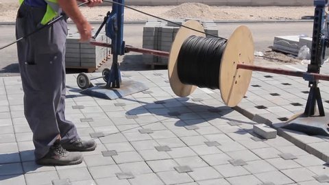 Worker unwinds cable spool.
Electrician is unwinding cable spool at construction site.
