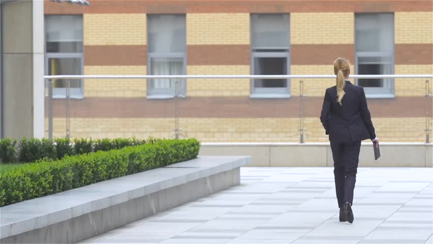 elegant business woman with tablet computer goes around office building. slow motion