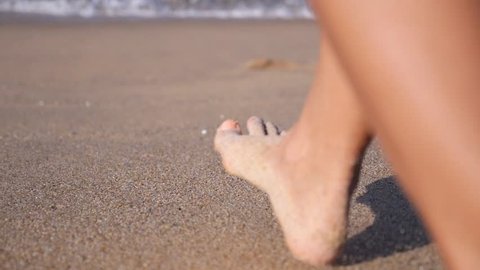 Woman Feet Walking on Beach Leaving Footprints in Sand