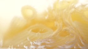Macro video of pasta in boiling water in a glass pan