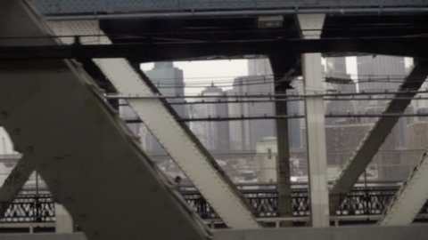 gritty shot of Lower Manhattan through bridge steel beams from moving subway train in NYC