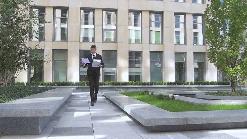 Young successful businessman throwing paper with arms in the air, slow motion
