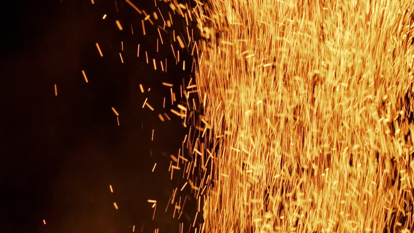 Lot of sparks from large bonfire in the night in slow motion. Beautiful abstract background on the theme of fire, light and life.