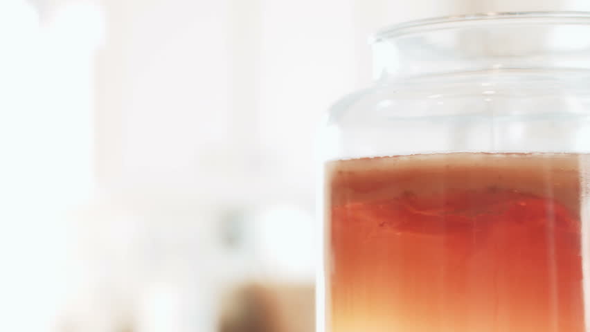 Kombucha and SCOBY closeup in a Jar ready for bottling and Young Woman Bringing Sugar and Black Tea for next Batch. | Shutterstock HD Video #14310025