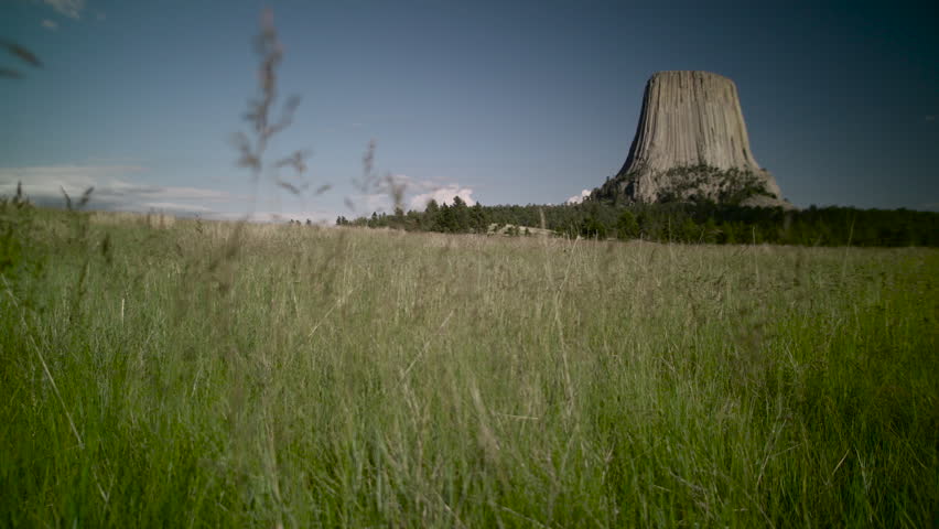 Panning Shot - Wide open view of Devils Tower in the background of the northeast Wyoming grasslands.