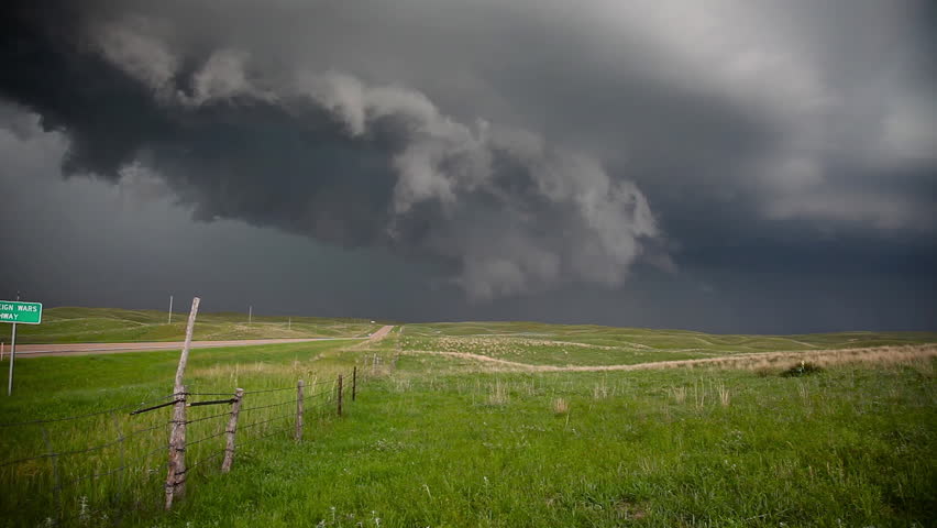 Rotating isolated supercell thunderstorm with shelf cloud over the American green grassy Great Plains of Nebraska.