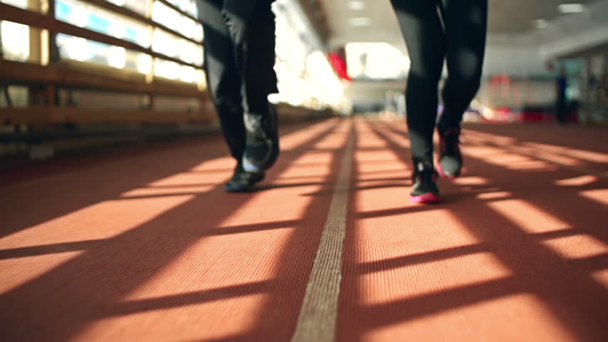 Close up of male and female legs running towards the camera on running track
