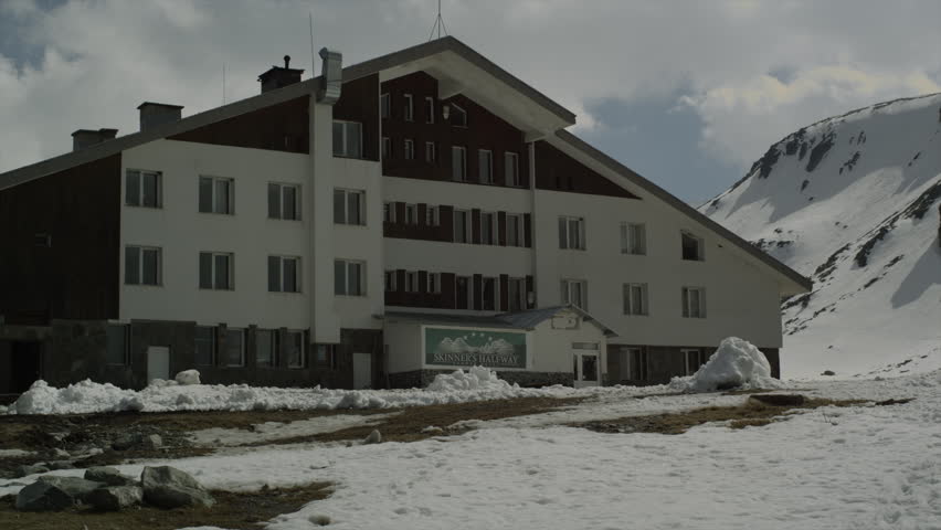 View of a House/Hotel/ Villa in the Mountain. A hotel/house/villa in the mountain. Big building. Snow on the ground. Winter. Clouds in the sky. daytime.