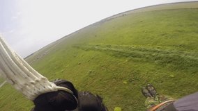 Parachutist in camouflage suit hitting hard the ground. View from the camera on helmet.