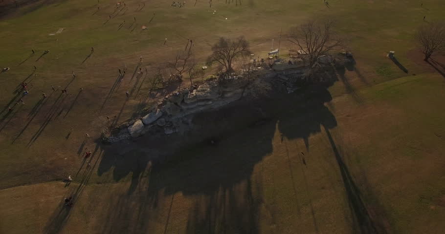 The camera starts at low altitude and moves forward as it crawls closer to athletes playing a pickup game of soccer.  The camera gains altitude and tilts down as it circles the players in Zilker Park.