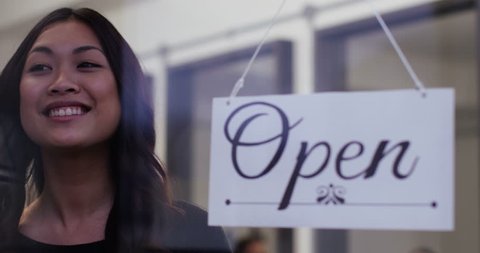 A beautiful woman proudly turns over an "open" sign in her shop window. Shot on RED Epic in slow motion.