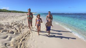 Family running on a sandy beach in Caribbean island
