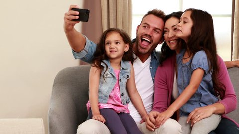 Happy family taking selfie on sofa at home