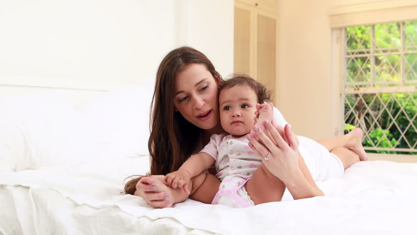 Happy mother playing with her baby on the bed