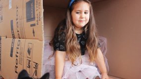 Video HD 1920x1080 Emotional facial expression beautiful face of happy girl. Portrait of emotional girl 5-s with long hair playing in a cardboard box. Little girl playing on the packaging container.