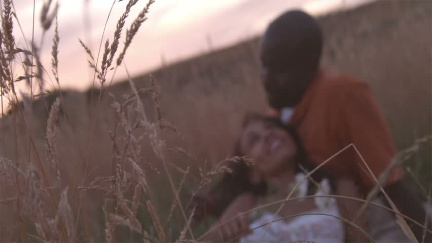 A 30-something couple enjoys a picnic and each other in a wheat field at dusk.