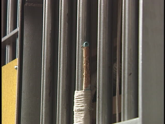 A prisoner places a letter between the bars on his prison-cell.