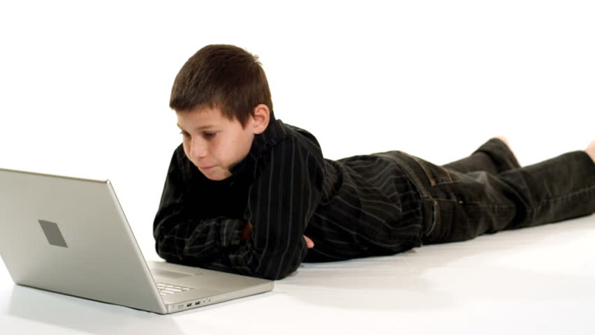 A young boy works on a laptop. After becoming confused, he realizes the solution