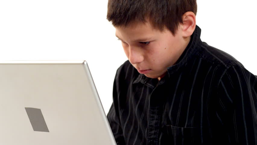 A young boy works on a laptop. After becoming confused, he realizes the solution